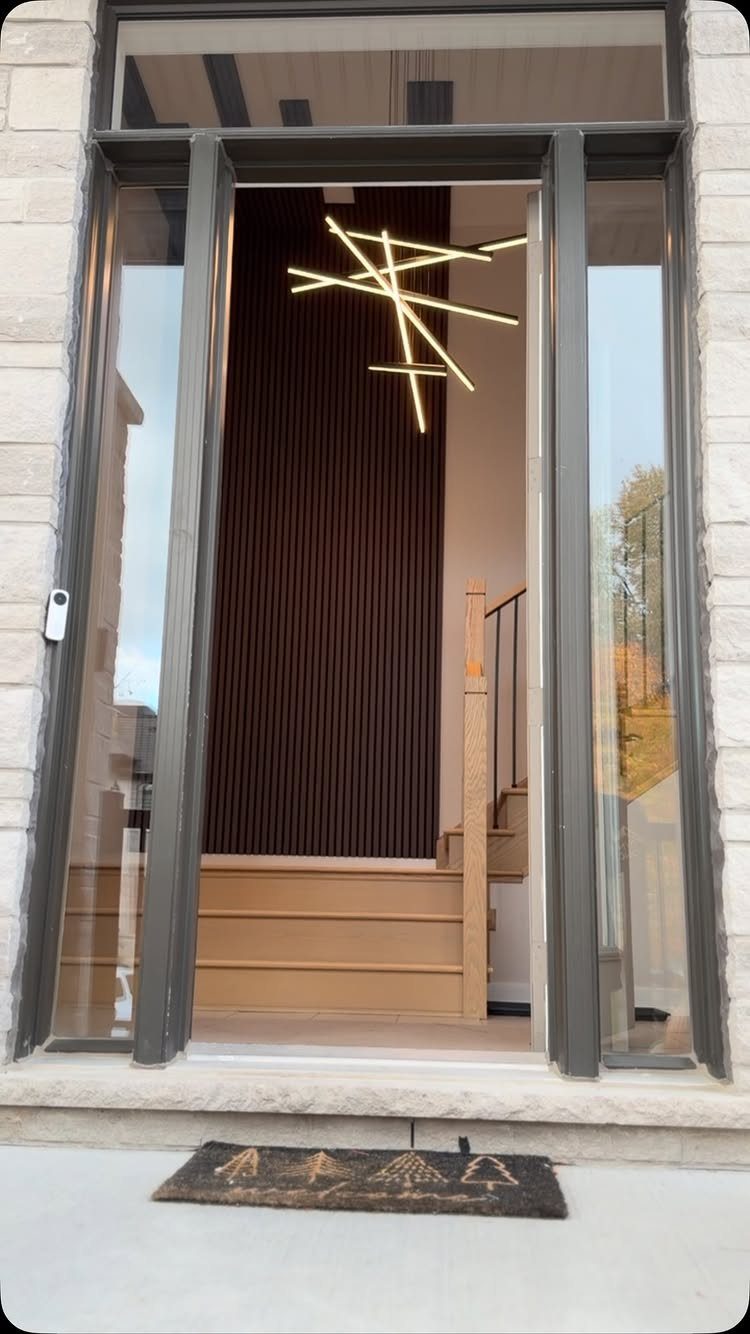 Dark brown floor-to-ceiling slatted wood panels in a modern home entryway with light wood stairs.