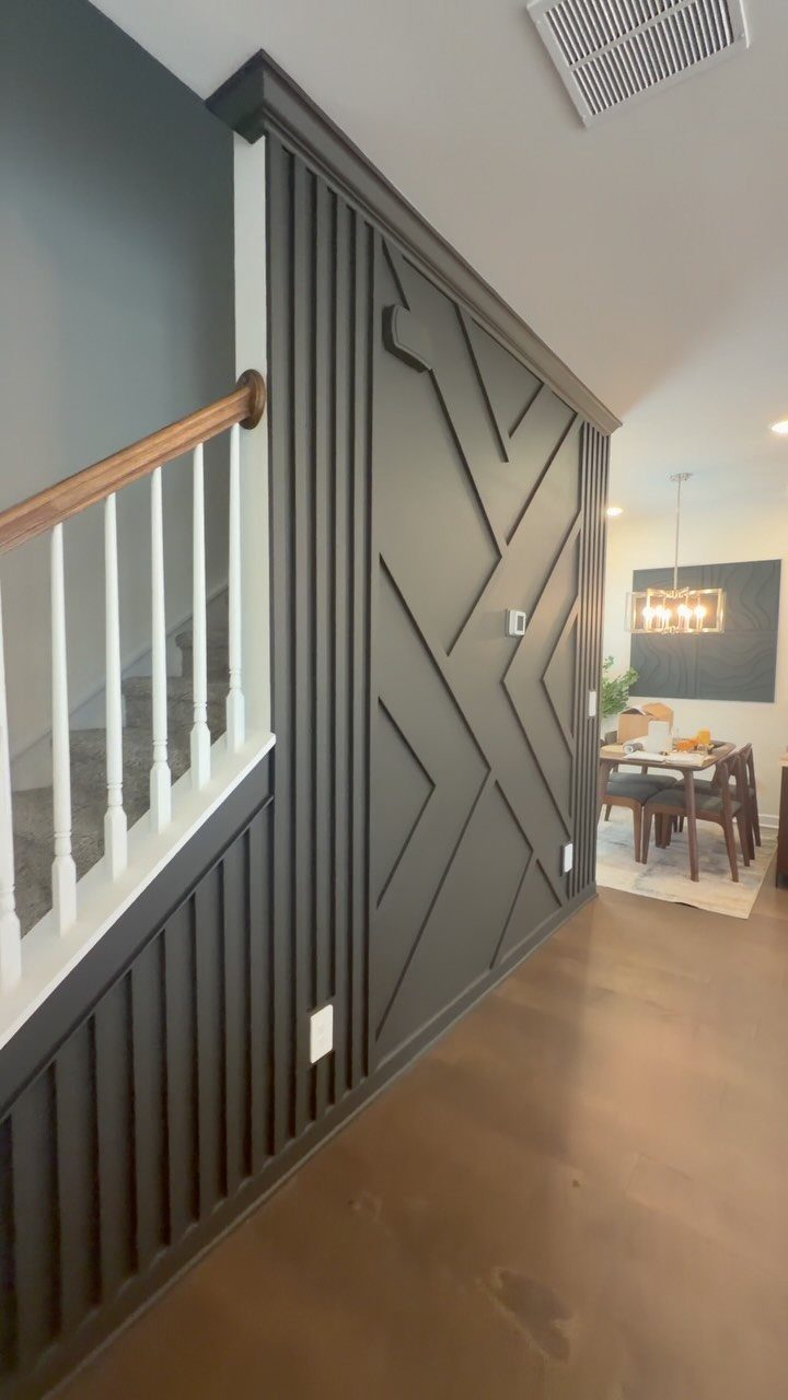 Dark grey accent wall featuring a custom geometric molding design in a modern hallway setting.