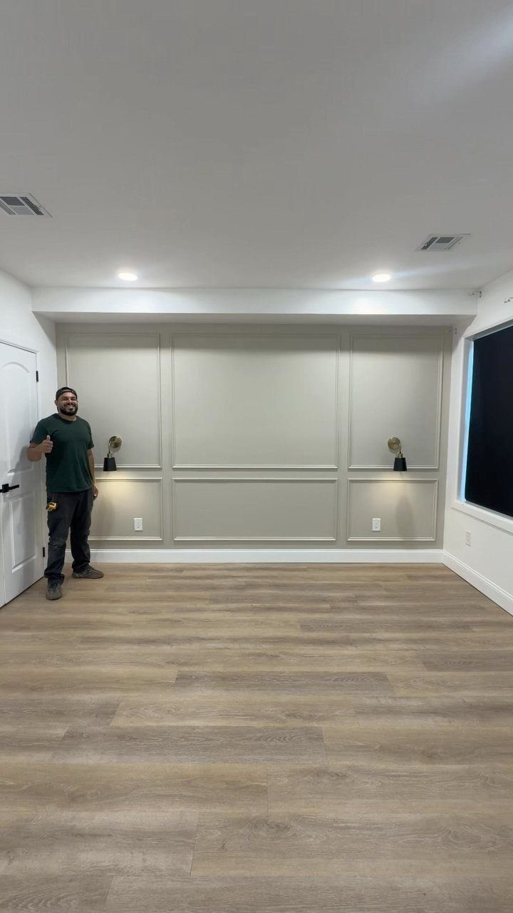 Man standing in a room featuring a grey accent wall with picture frame molding.