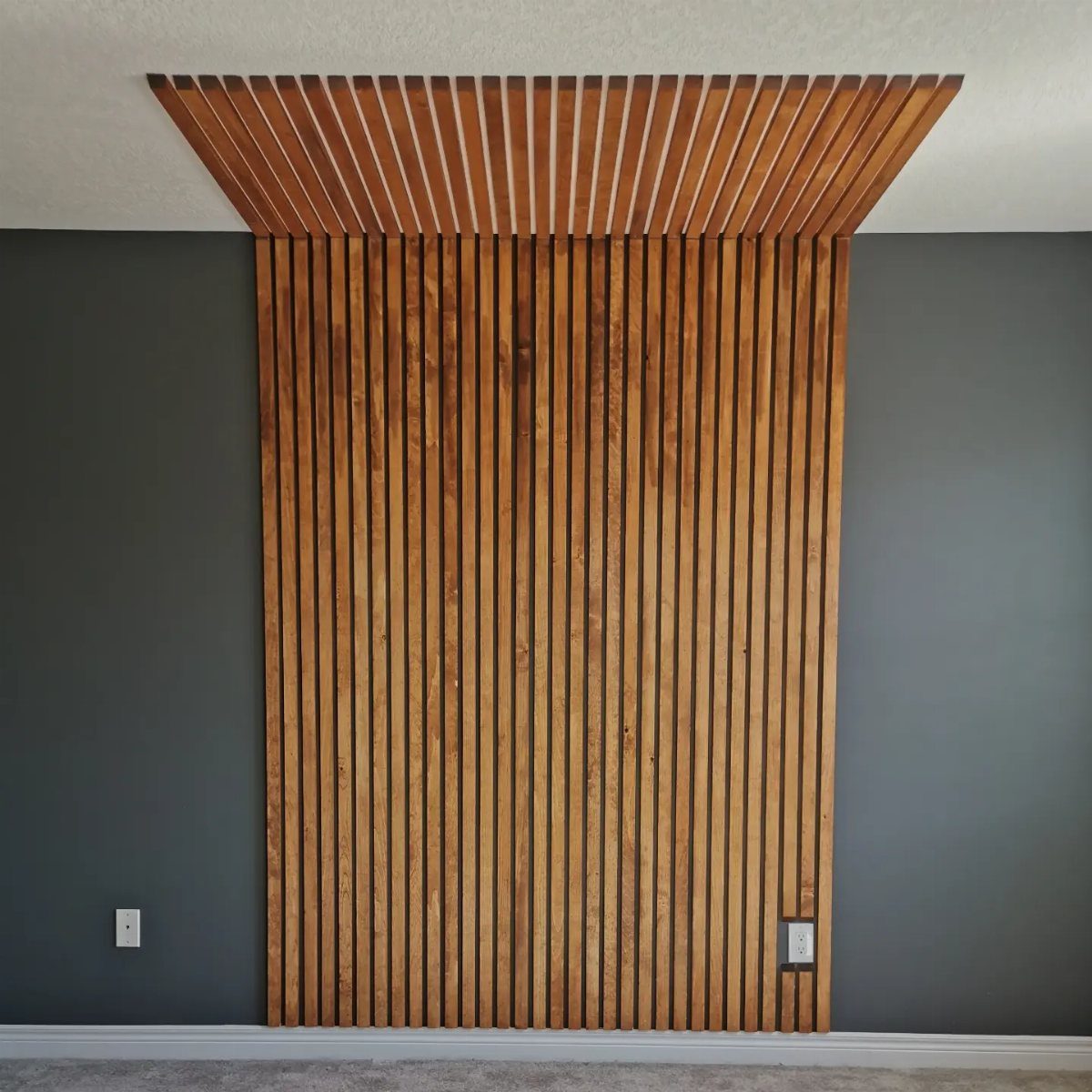 Vertical wooden slats forming an accent wall and ceiling feature on a grey wall.