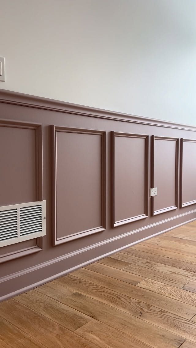 Mauve picture frame wainscoting panels installed on a wall above light wood flooring.