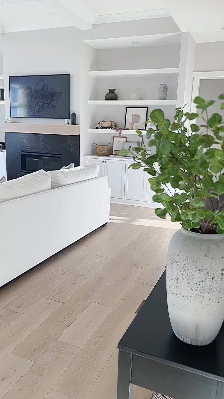 Light wood plank flooring in a bright, modern living room with white furniture and decor.
