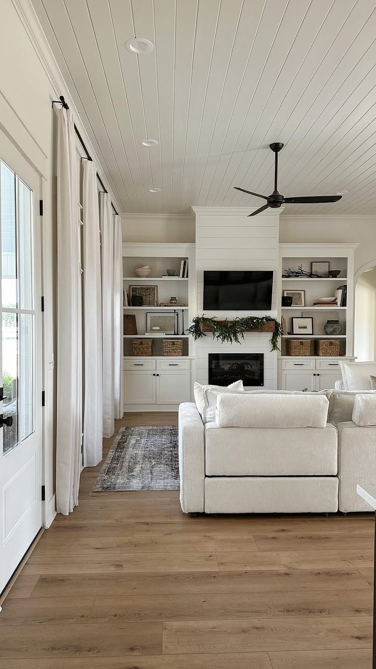Light brown wood-look plank flooring in a bright, modern living room with white furniture.