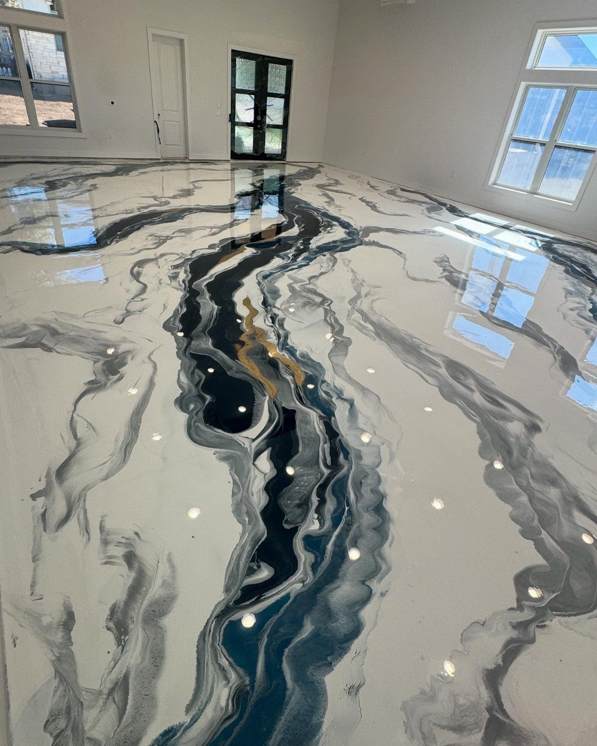 Polished epoxy flooring with swirling blue, grey, and white marble patterns in a bright room.