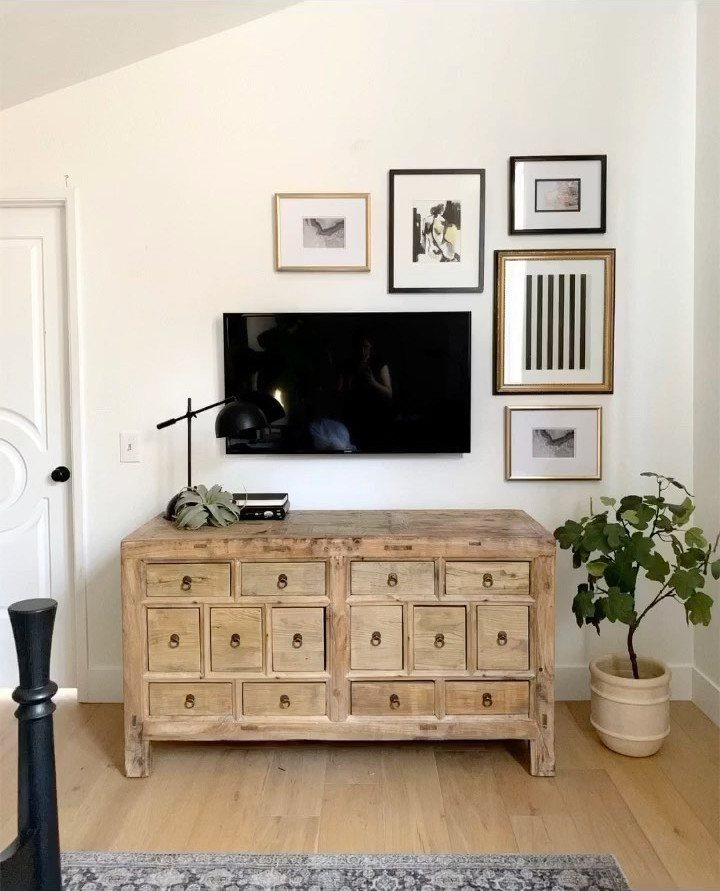 Framed black and white art pieces arranged in an asymmetrical layout on a white wall.