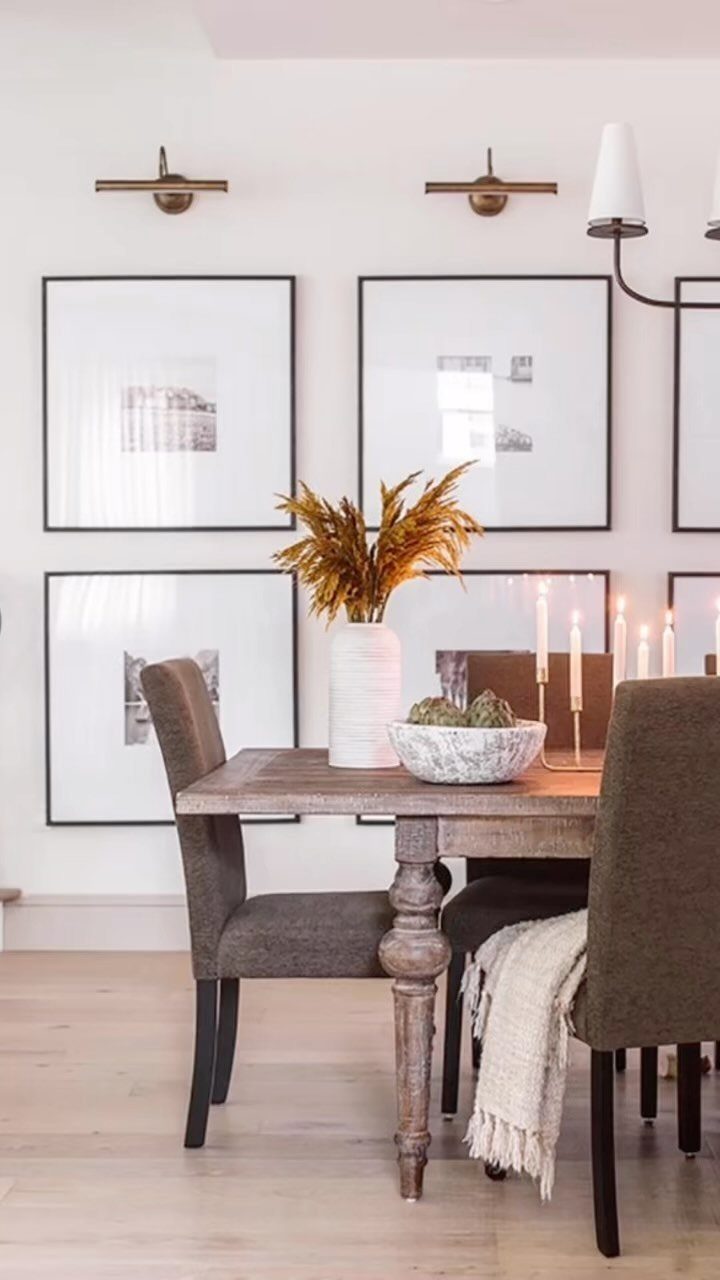 Four large black-framed artworks arranged in a perfect grid on a white wall above a dining table.