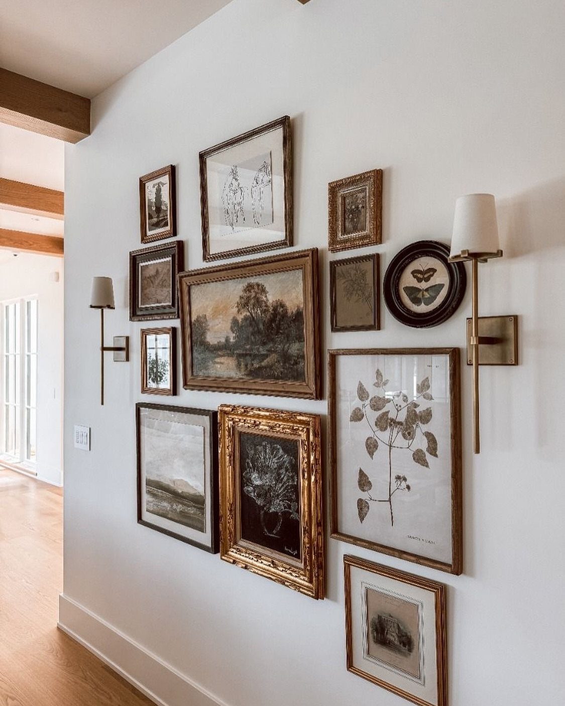 Various framed artworks of different sizes and styles arranged in a gallery wall on a white wall.