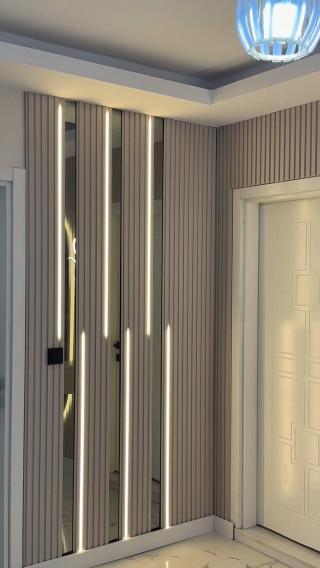 Vertical wood slats on a hallway wall with integrated glowing LED light strips.