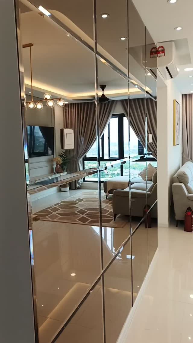Mirrored wall panels reflecting a modern living room with a sofa and large windows.