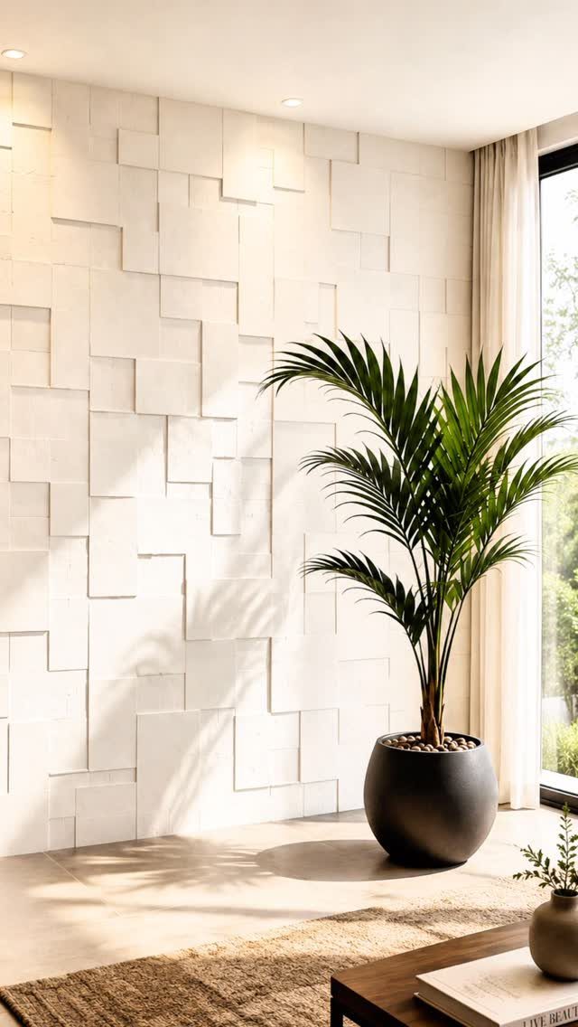 A white wall with a 3D geometric textured pattern next to a large potted palm plant.