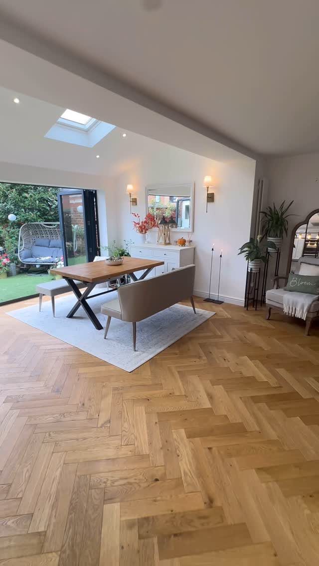 Light wood flooring in a herringbone pattern covers the floor of a bright dining room.
