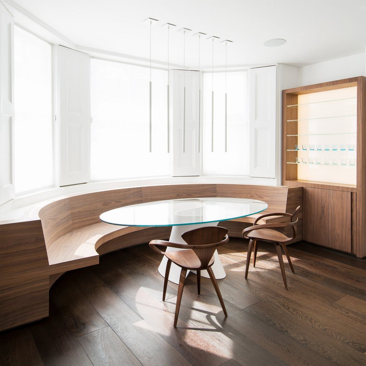Wide dark wood planks flooring in a bright modern dining room with curved wooden seating.