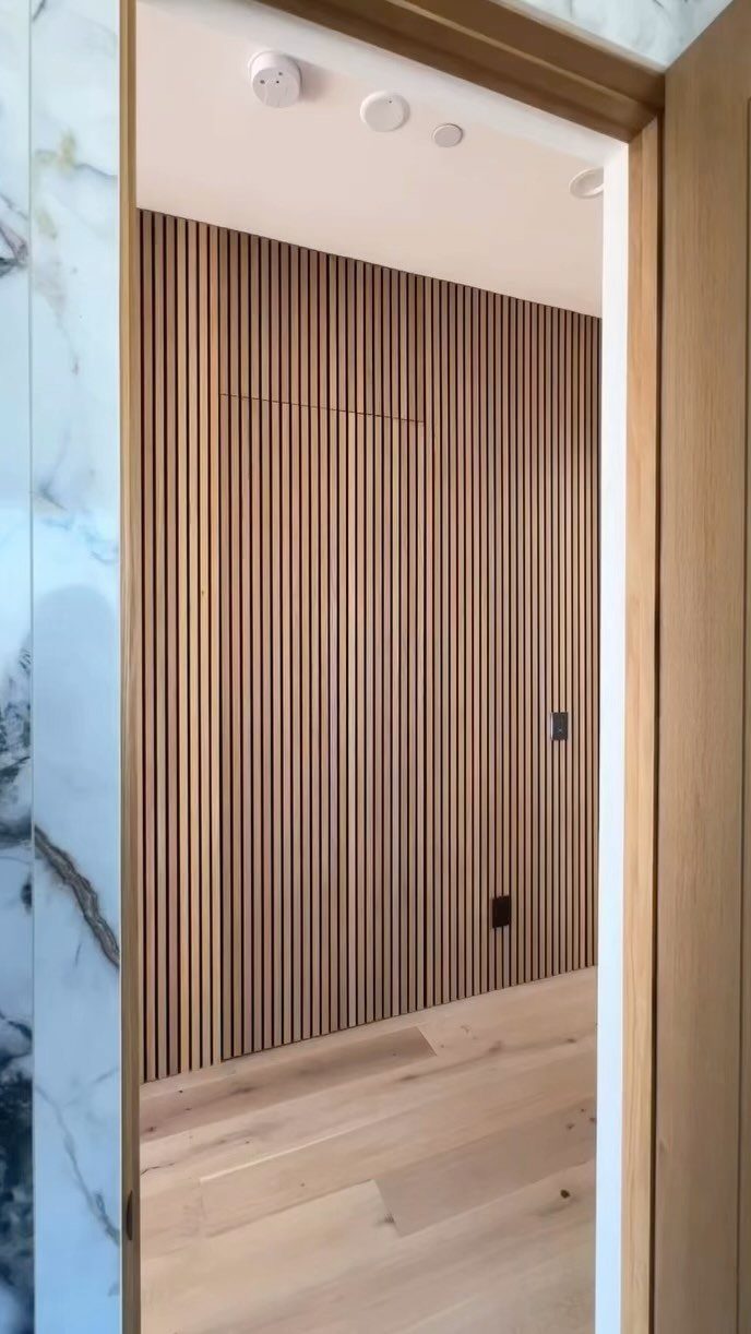 Vertical light oak fluted wood panels covering a wall in a modern interior space.