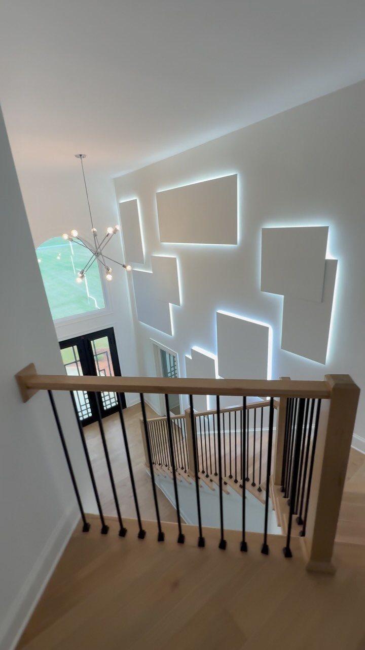 Geometric white wall panels with glowing backlight installed in a modern home entryway.