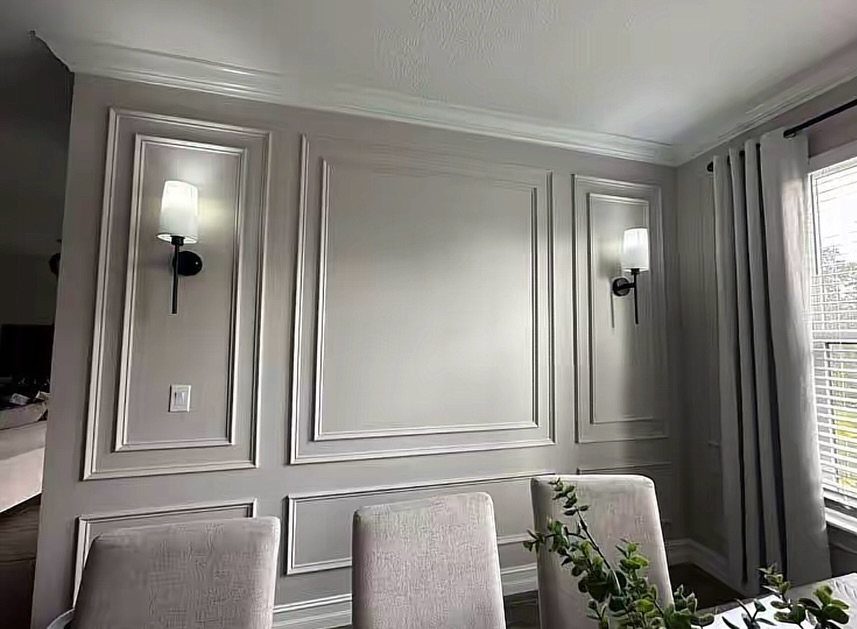 Grey walls decorated with elegant rectangular picture frame molding and white wall sconces.