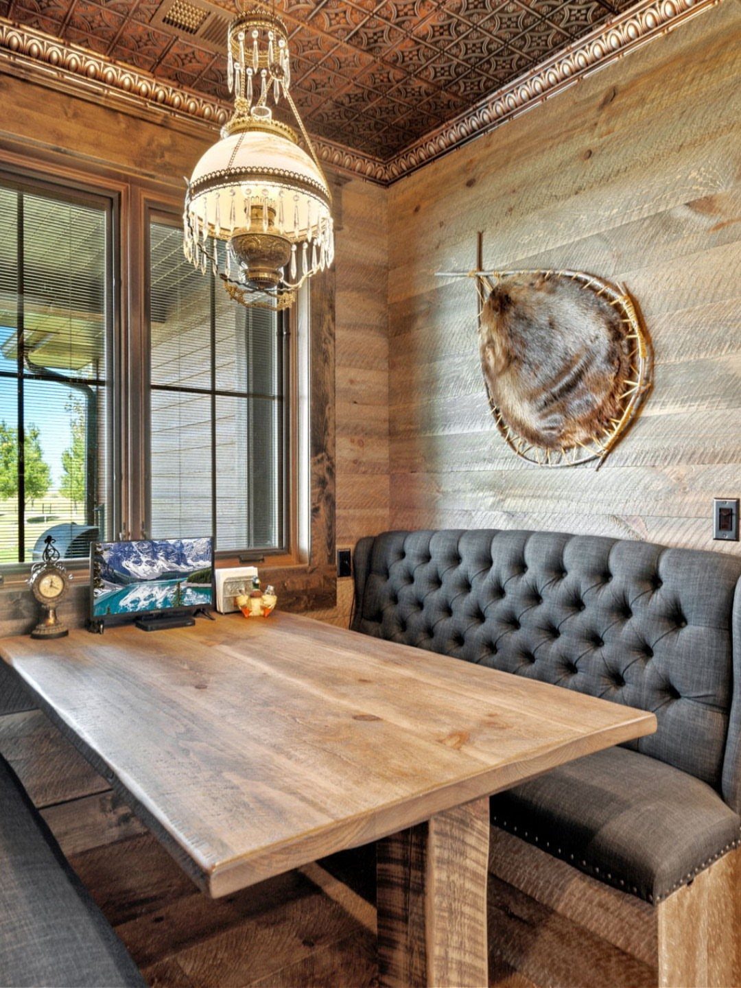 Natural wood planks covering the walls in a dining room with a wooden table and grey banquette.