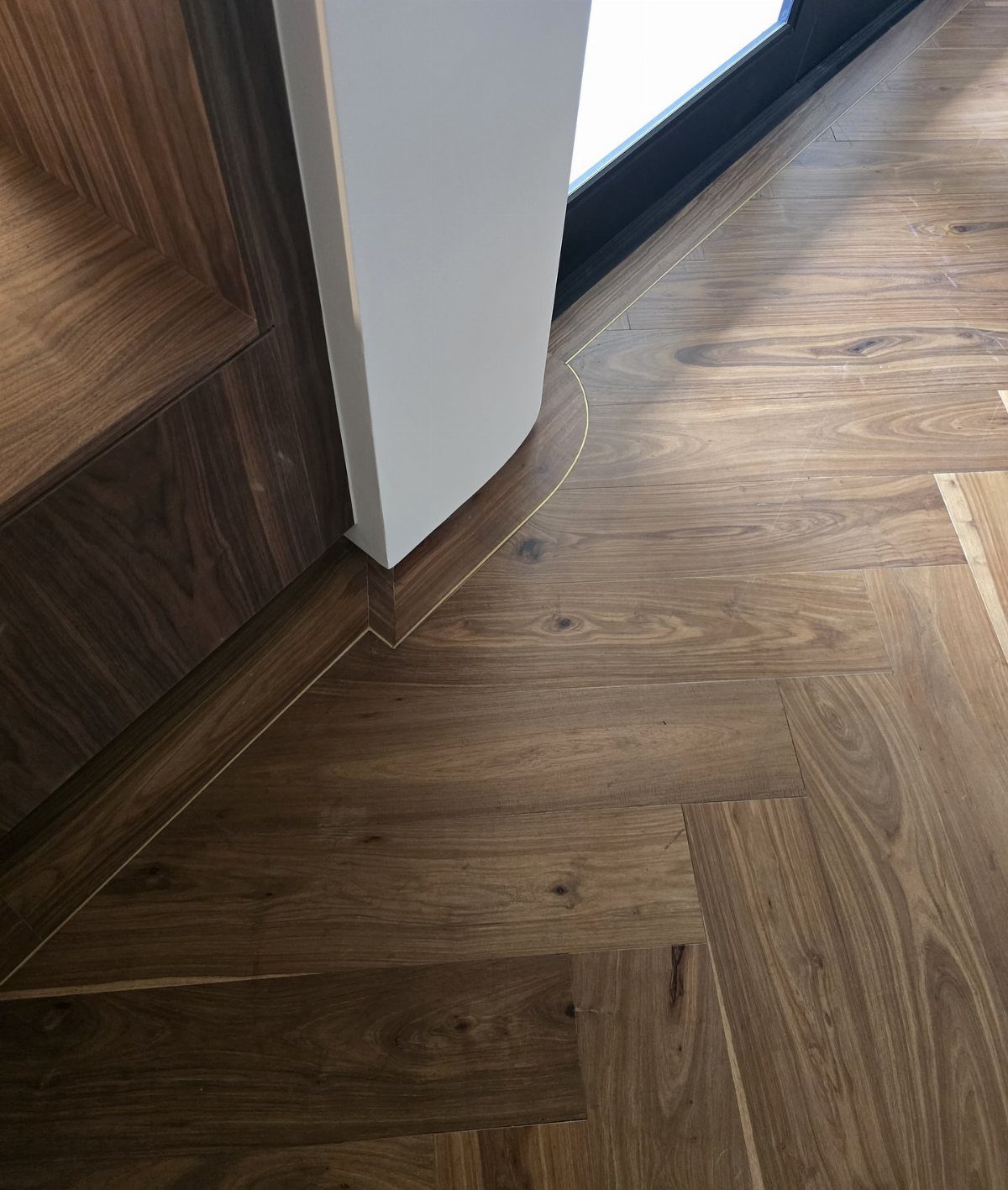 Walnut wood flooring in a herringbone pattern with rich brown tones and natural grain.
