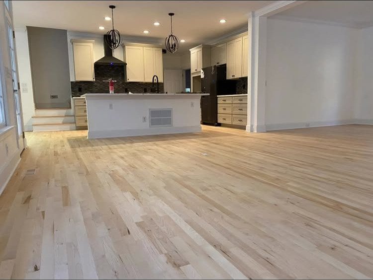 Light maple hardwood flooring in a spacious, modern open-concept kitchen and living area.