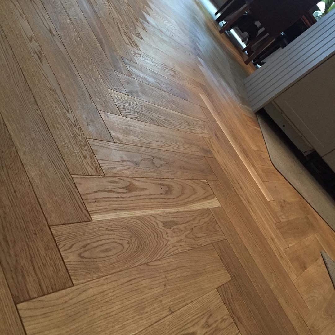 Light oak wood flooring featuring a central herringbone pattern transitioning into straight planks.