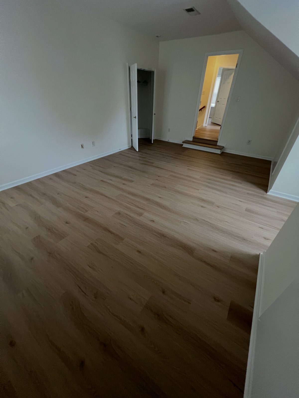 Light brown wood plank flooring installed in an empty room with white walls.