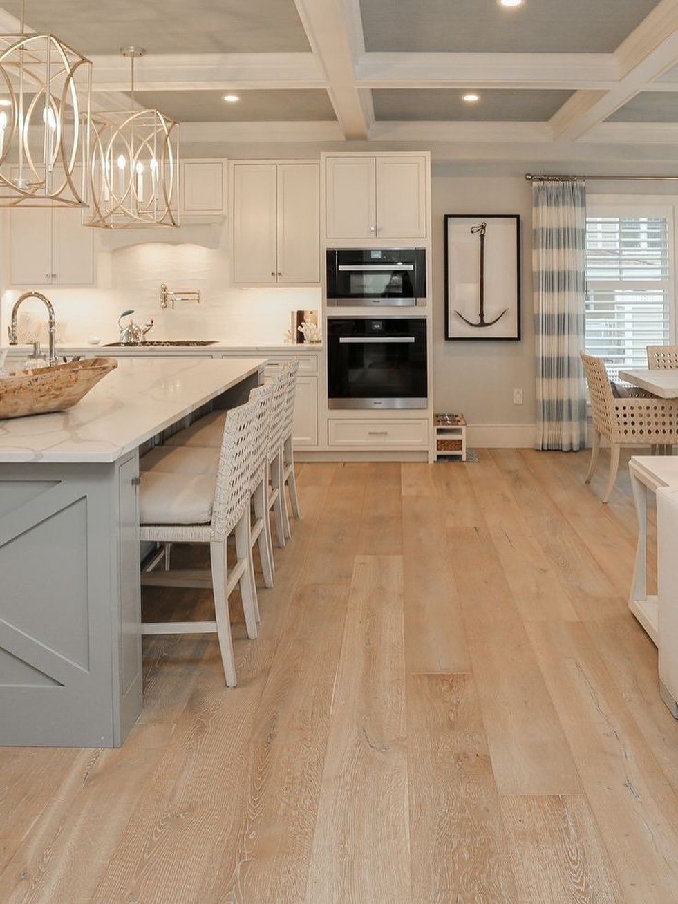 Light beige wood-effect flooring in a bright, modern kitchen with white cabinets and a grey island.