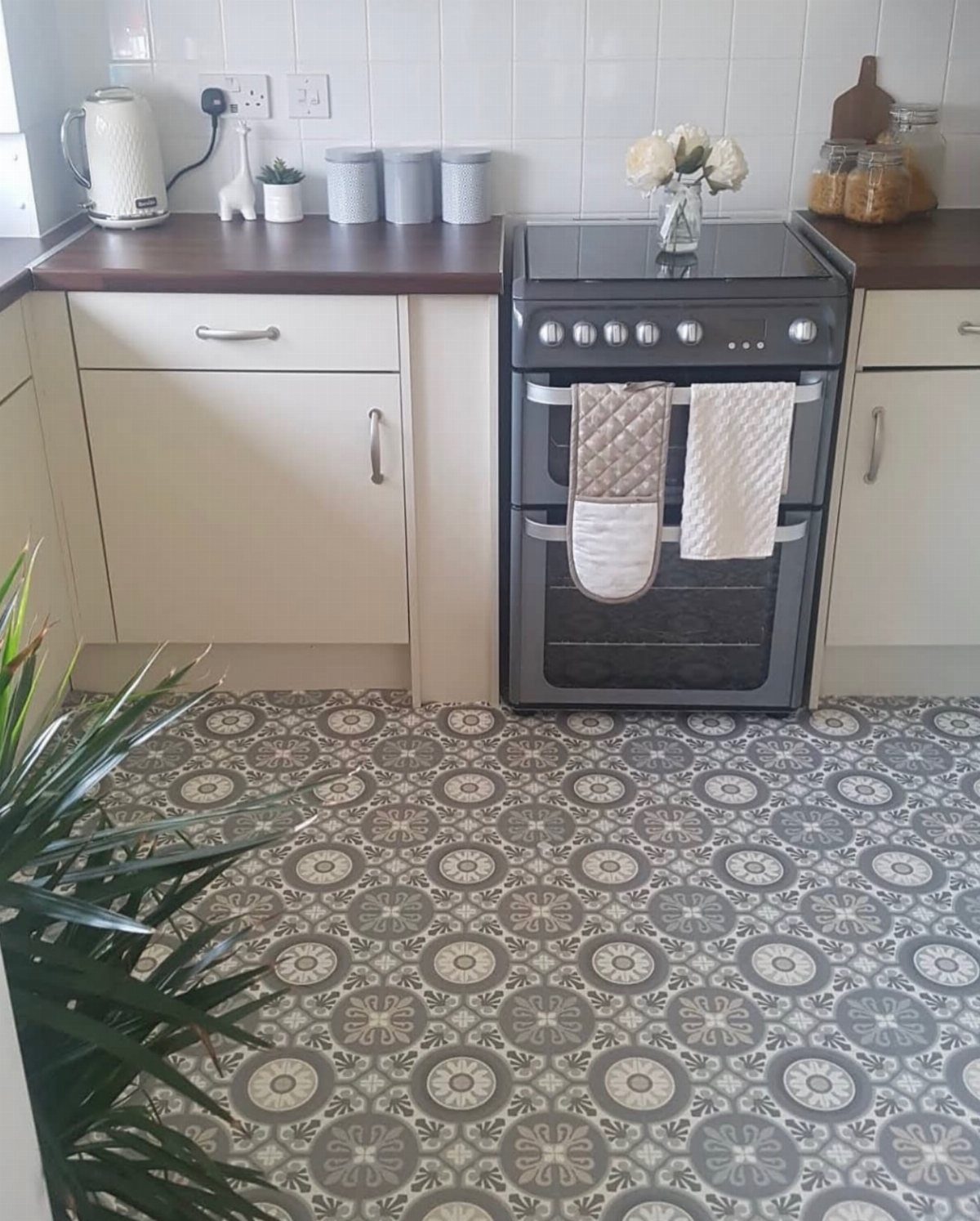 Patterned grey and white circular motif vinyl flooring in a modern white kitchen setting.