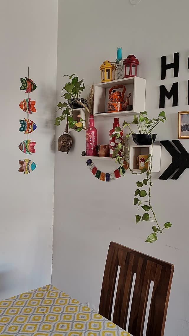 14 Wall Design in Living Room Ideas That Add Real Depth 2 Colorful fish decorations and white floating shelves with plants and lanterns on a white wall.