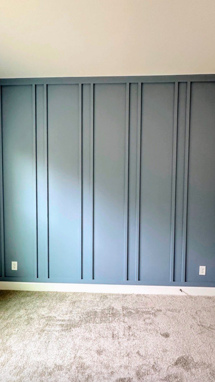 Blue board and batten wall paneling with vertical wooden strips in a room.