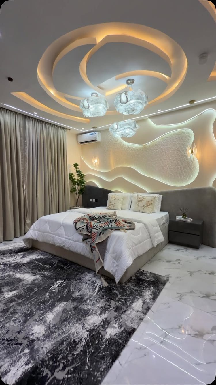 Modern bedroom with wavy backlit wall paneling, a large bed, and decorative recessed ceiling lighting.