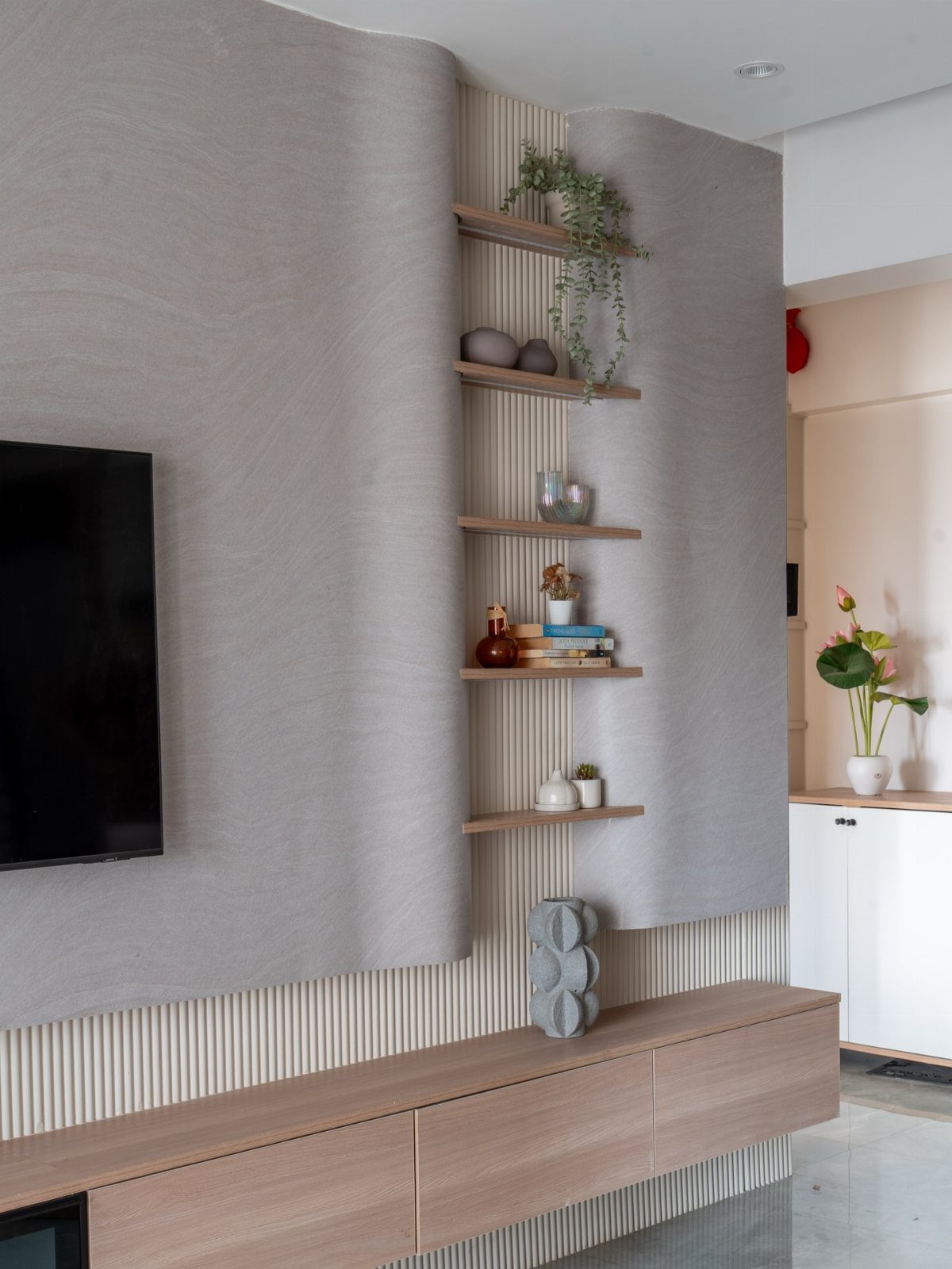 Curved grey textured wall panels with wooden shelves and a floating console unit.