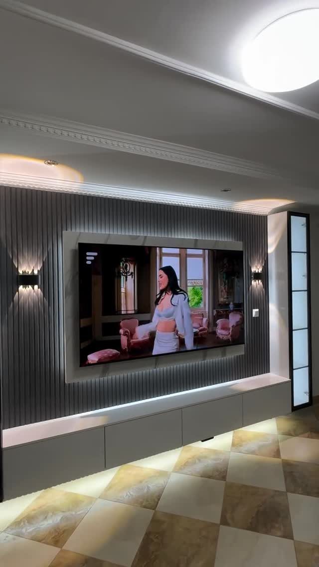A large television mounted on a dark ribbed wall panel above a white floating media console.