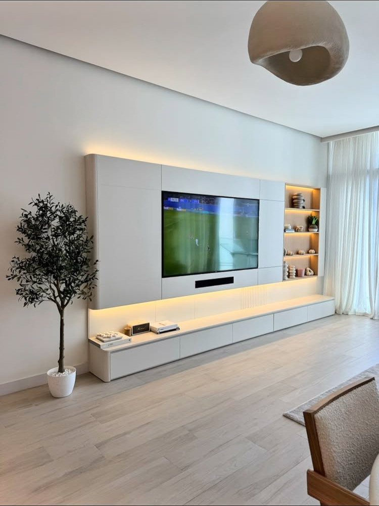 White modern TV unit with integrated LED lighting and open shelves on a white wall.