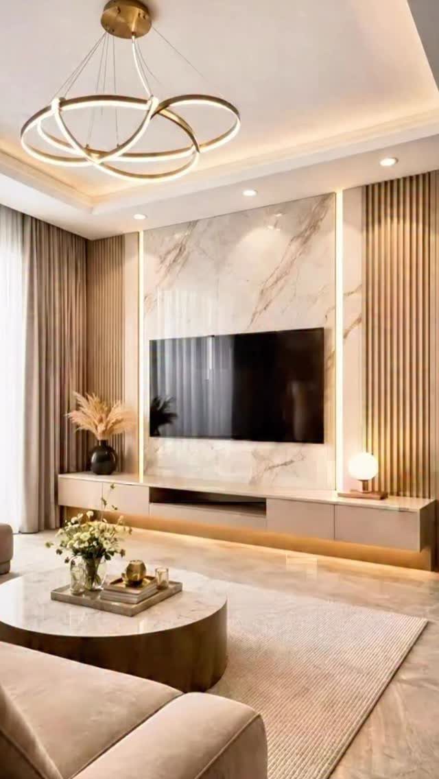 Marble TV wall panel with a long modern console and gold circular chandelier.