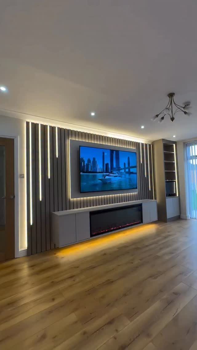 Modern wall TV panel with vertical slats, LED lighting, a television, and an electric fireplace.