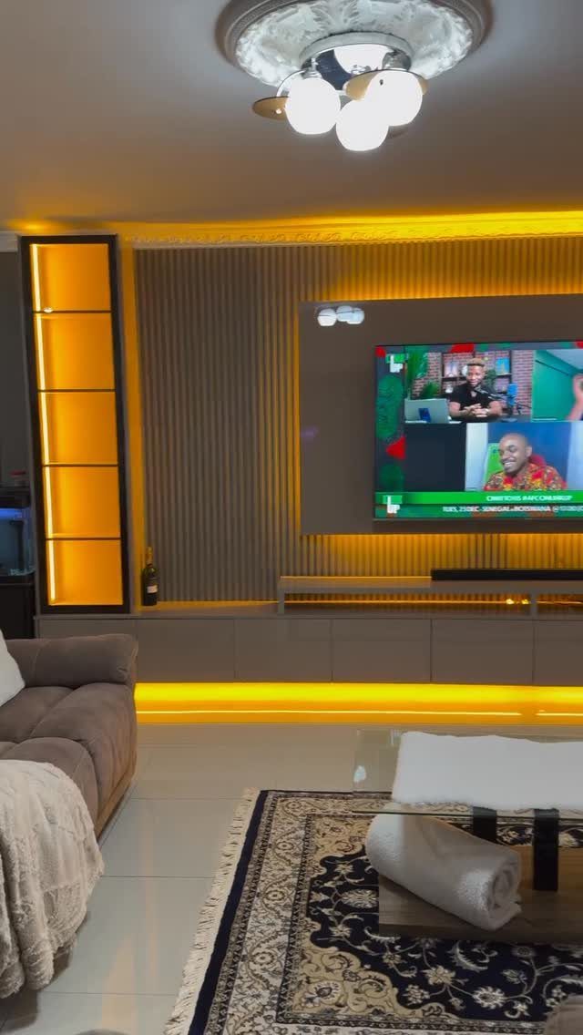 Modern living room wall unit with integrated yellow LED backlight strips and grey vertical slats.