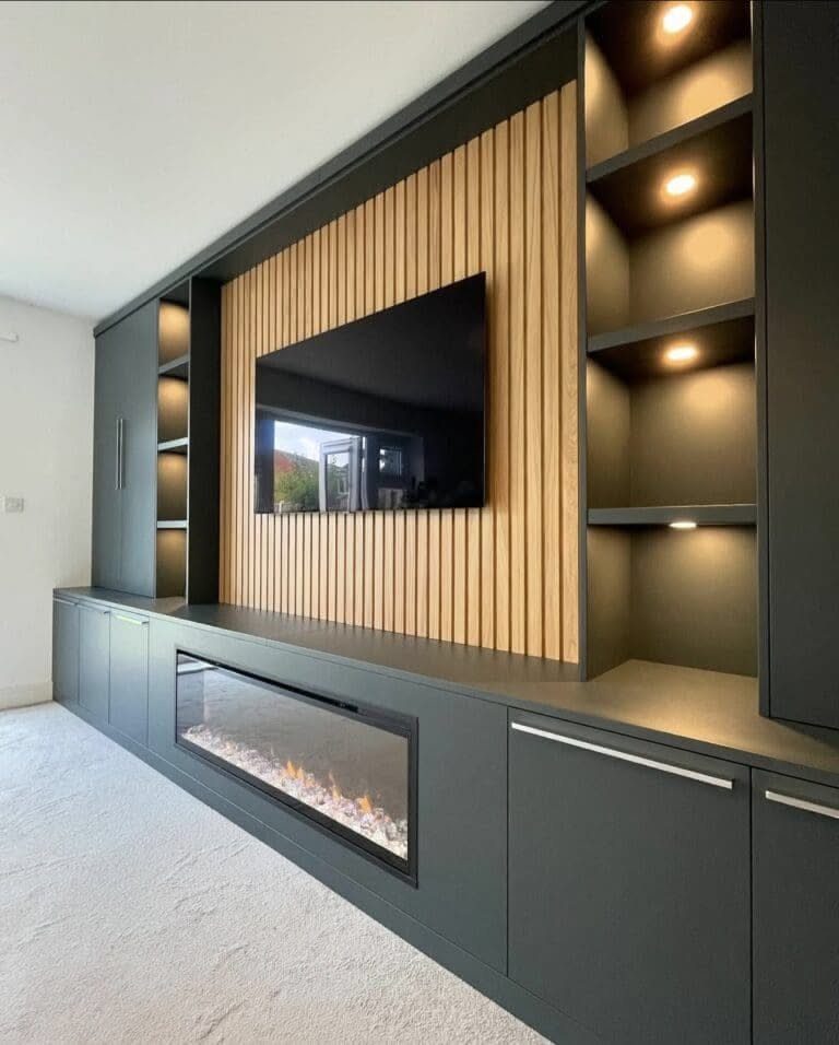 Dark grey built-in wall unit with wood slats, integrated shelving, and a modern linear fireplace.