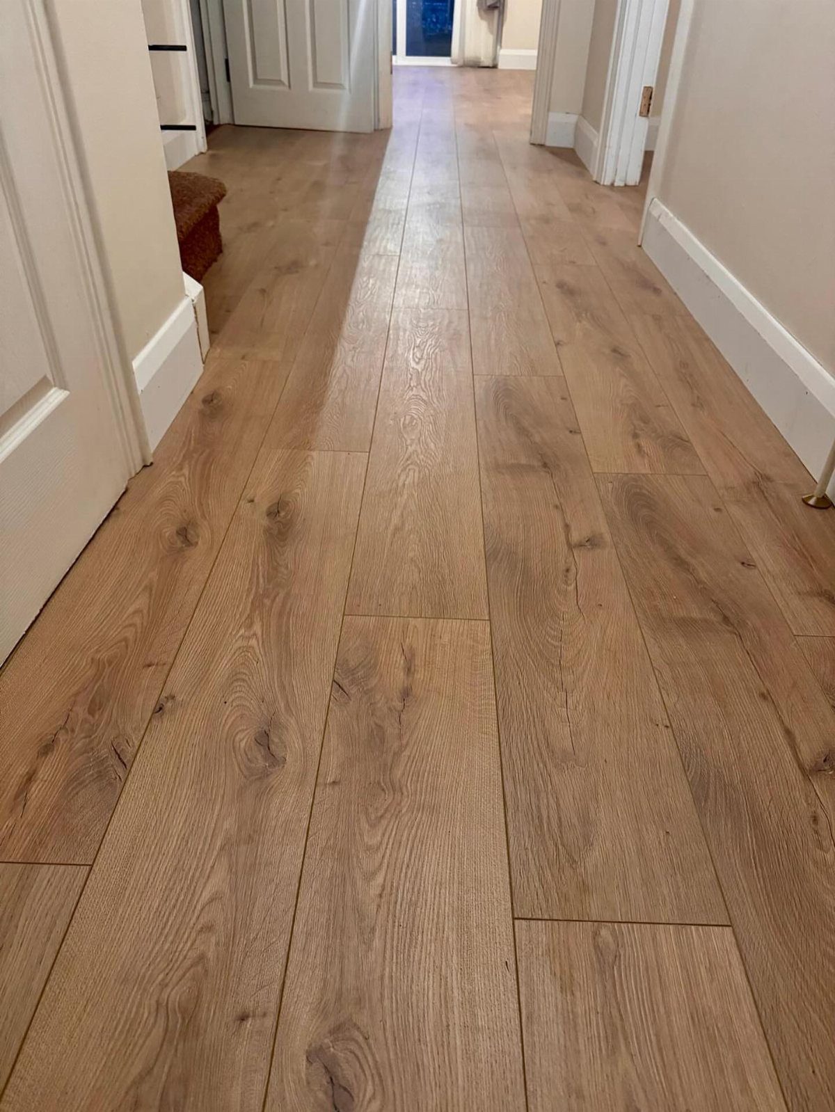 Light honey-toned wood planks with natural grain running through a bright hallway.