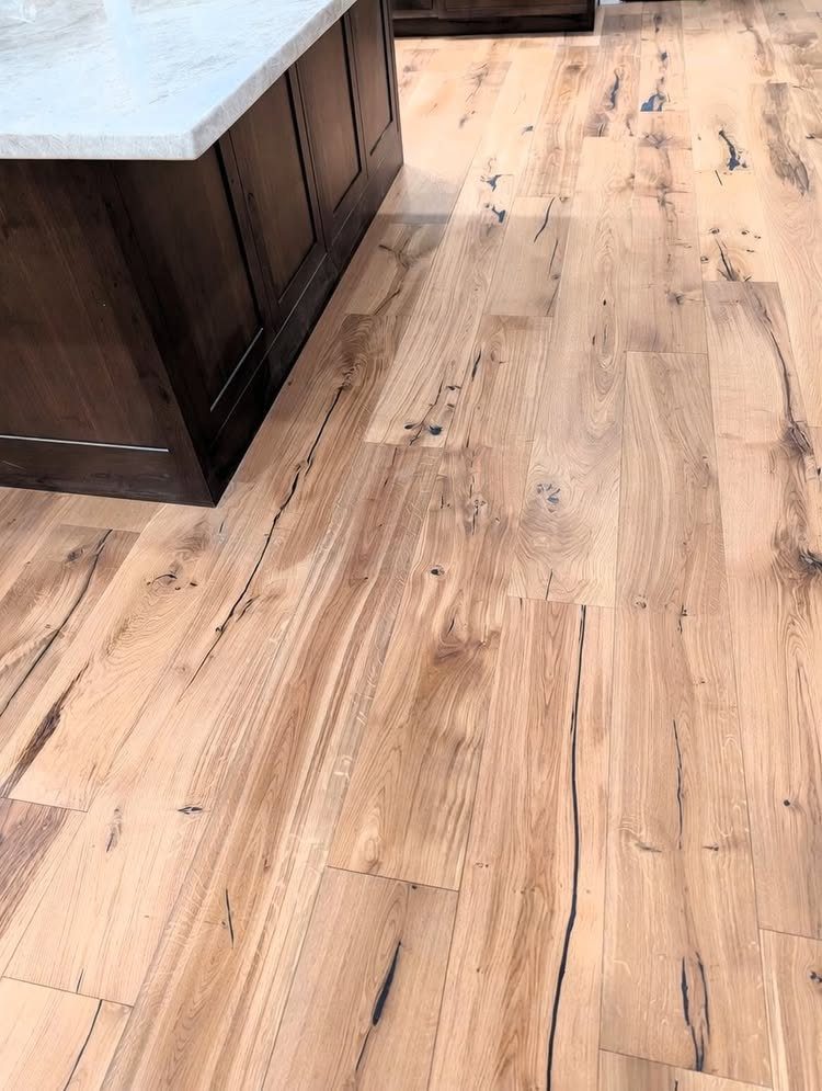 Light natural oak wood flooring with prominent grain and knots in a kitchen setting.