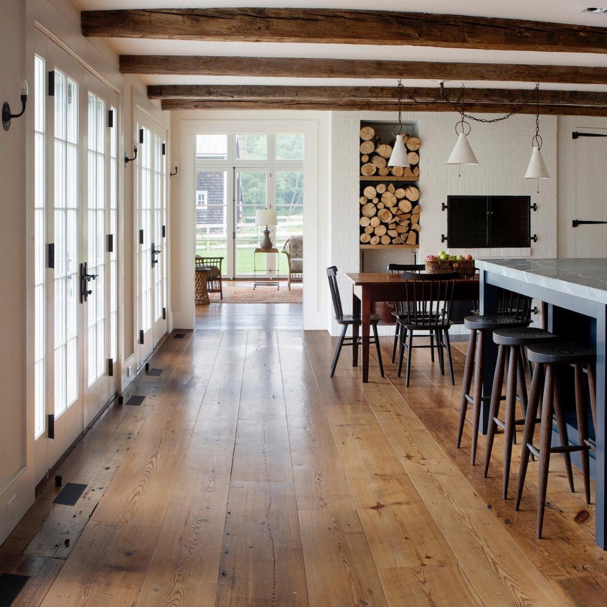 Wide plank reclaimed wood flooring stretching through a bright, modern farmhouse kitchen and hallway.