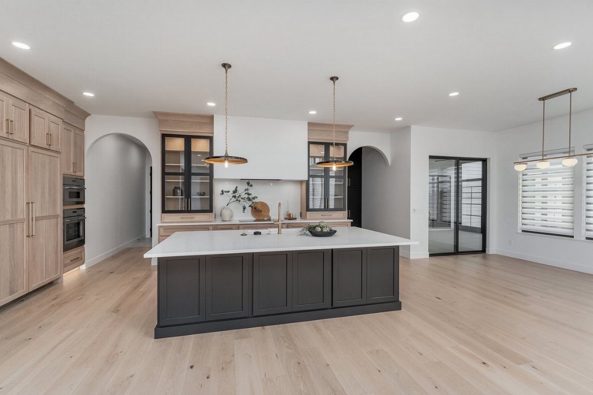 Modern kitchen with a dark grey island and light white oak wood floors.
