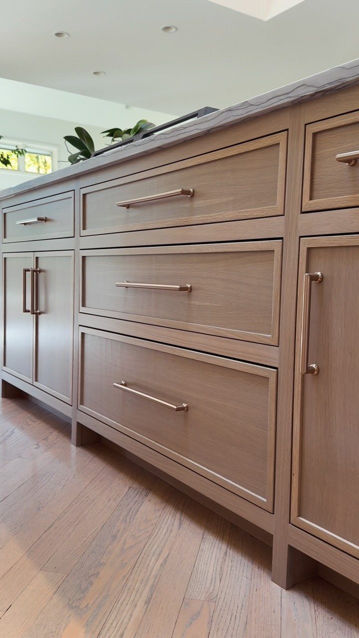Light wood kitchen cabinets with sleek metal handles above wooden floors.