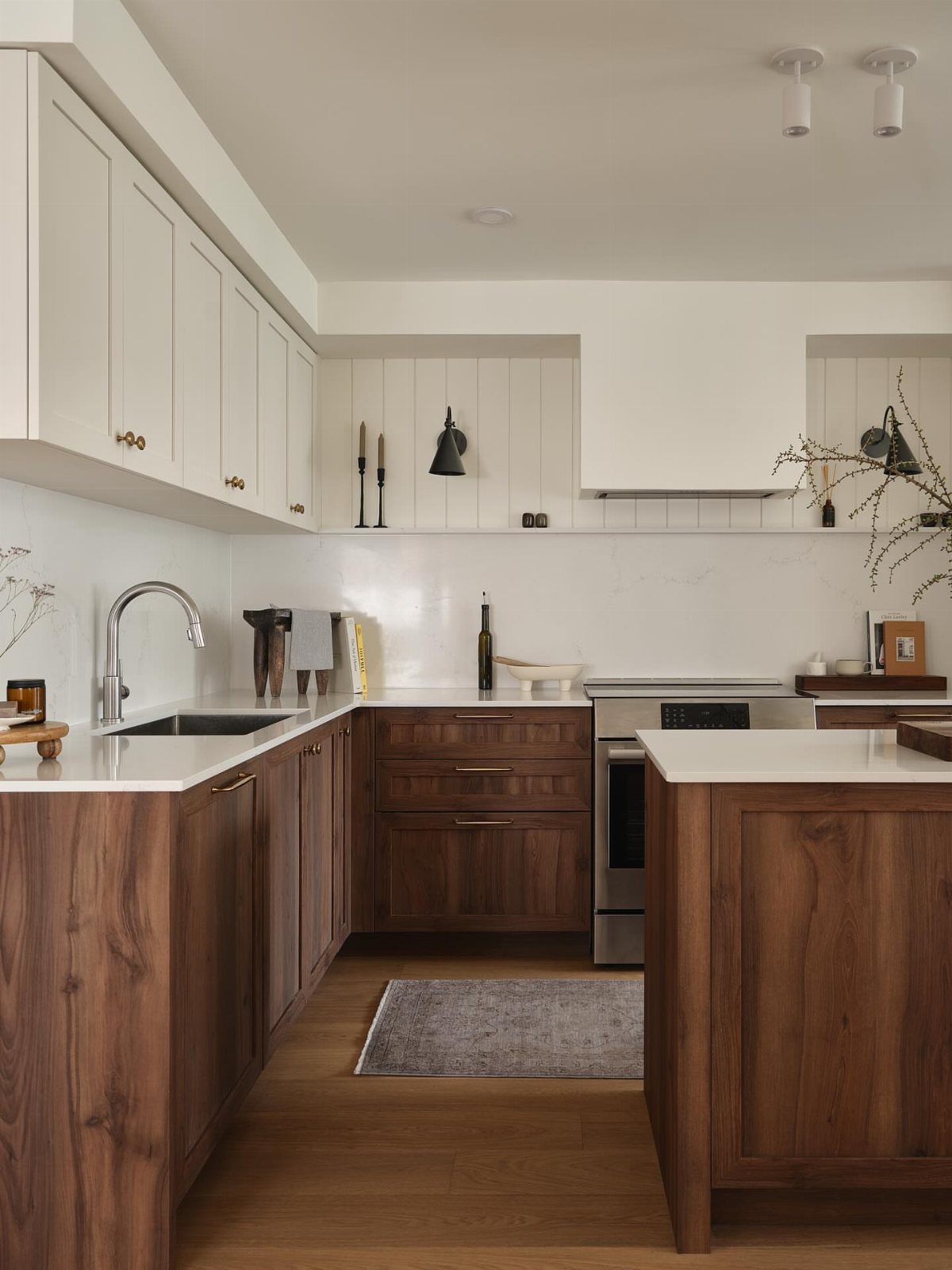 Modern kitchen featuring white upper cabinets and dark wood lower cabinets with white countertops.
