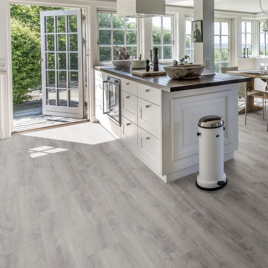 Light gray wood-look flooring in a bright, modern kitchen with white cabinets.