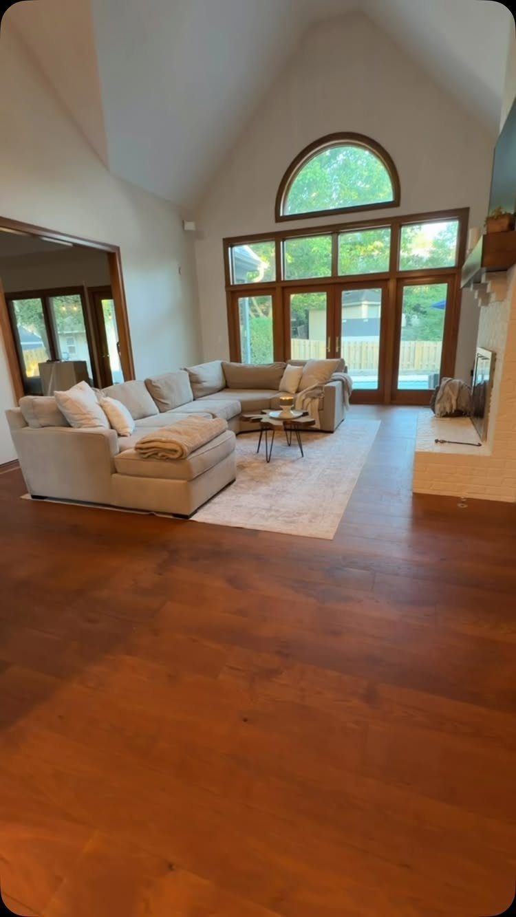 Warm reddish-brown hardwood flooring in a spacious living room with a beige sectional sofa.